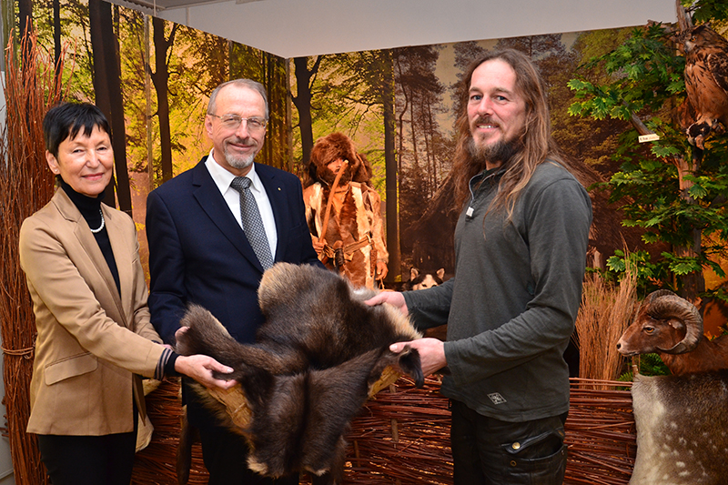Ausstellungseröffnung der anderen Art: Ötzi schaut zu, wie Barbara Strobel (l.), Bürgermeister Roland Schäfer und Henning Fenner (r.) Hand an das Fell legen.