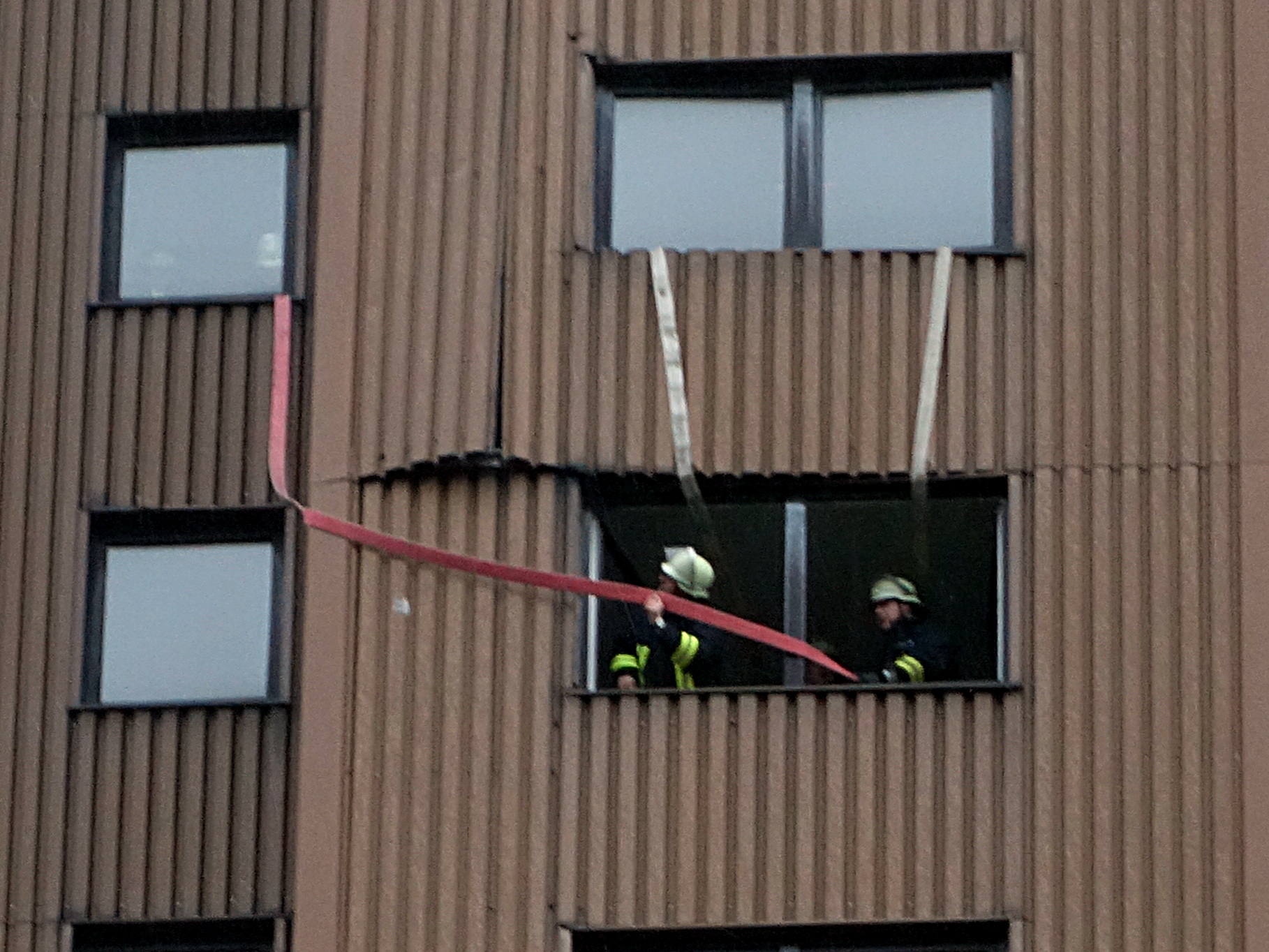 Mit mehreren Feuerwehrschläuchen sicherten Einsatzkräfte der Löschgruppe Weddinghofen mehrere Platten der Metallaußenverkleidung des Wohnturms, die wegen des Sturm von der 9. Etage in die Tiefe zu stürzen drohten.